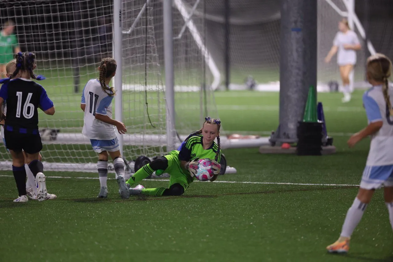 Goalkeeper diving to make a save during an evening game